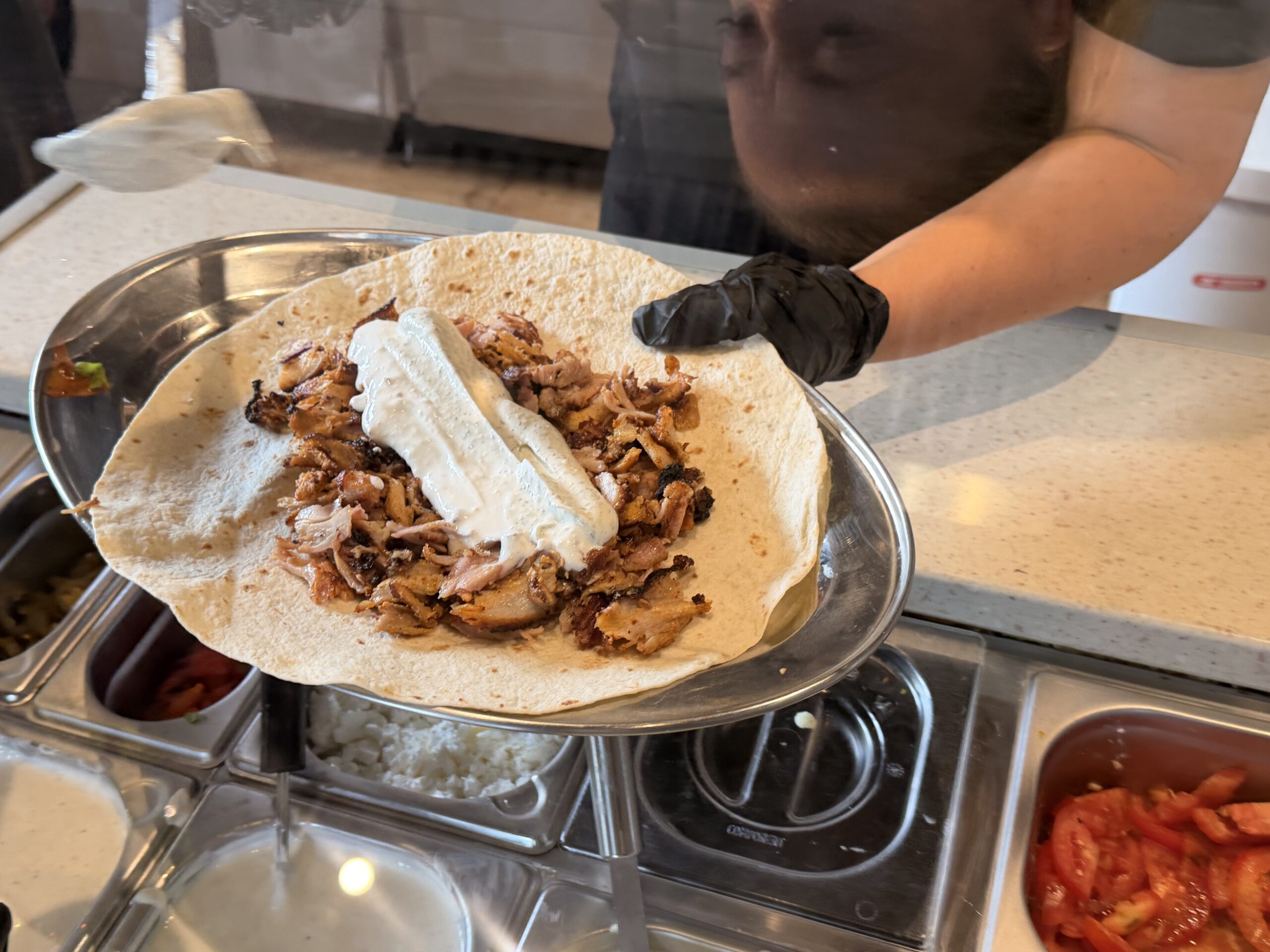Meat and sauce added to a wrap at Que?bab in Pueblo Nuevo